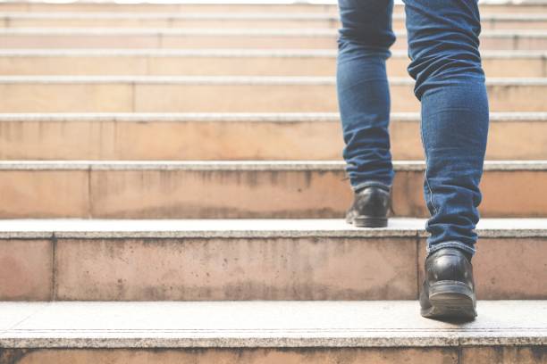 Close up legs shoes of young business man One person walking stepping going up the stairs in modern city, go up, success, grow up. with filter Tones retro vintage warm effect. stairway stock photo