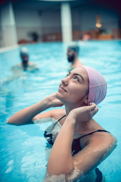 mujer preparando gorra de natación mientras disfruta del tiempo en la piscina con amigos - sports venue luxury love enjoyment fotografías e imágenes de stock