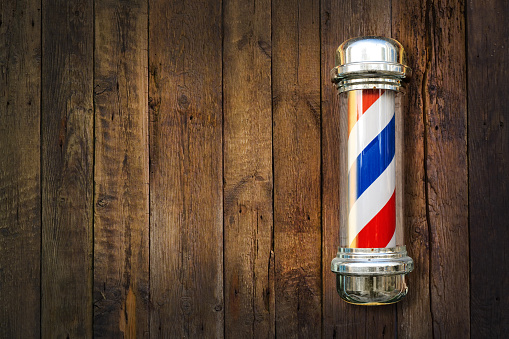Barber pole. Barbershop pole on a wooden background with copy space.