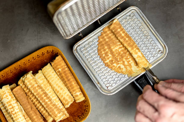 istock Cooking waffles at home - waffle maker. A man's hand rolls a wafer. Ready-made waffles on a plate. Culinary background. Step-by-step instructions. step 3 1292922438