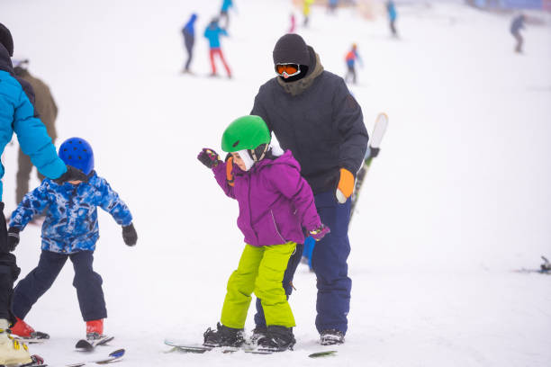 istock Instructors teach a child on a snow slope to snowboard 1292926345
