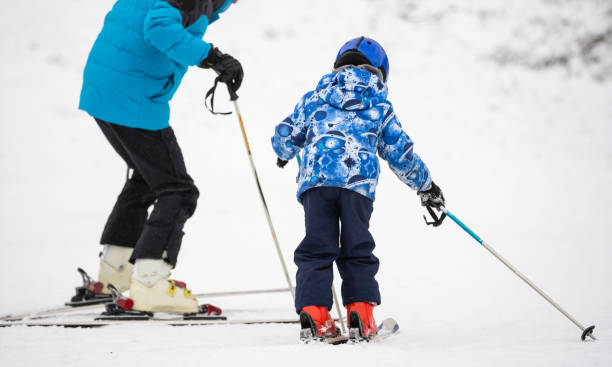 istock Professional ski instructor is teaching a child to ski on a day on a mountain slope resort with snow. Family and children active vacation. 1292926483