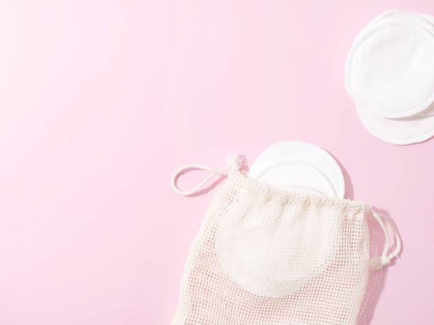 istock organic cotton pads with string bag on pink background. Zero waste, reusable, eco, makeup remover and washing concept. pattern, hard light, flat lay, copyspace 1292927136