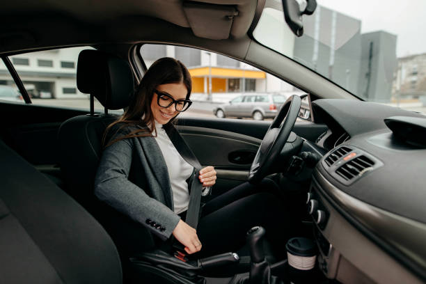 foto einer geschäftsfrau, die in einem auto sitzt und ihren sicherheitsgurt anlegt - seat belt safety protection driving stock-fotos und bilder