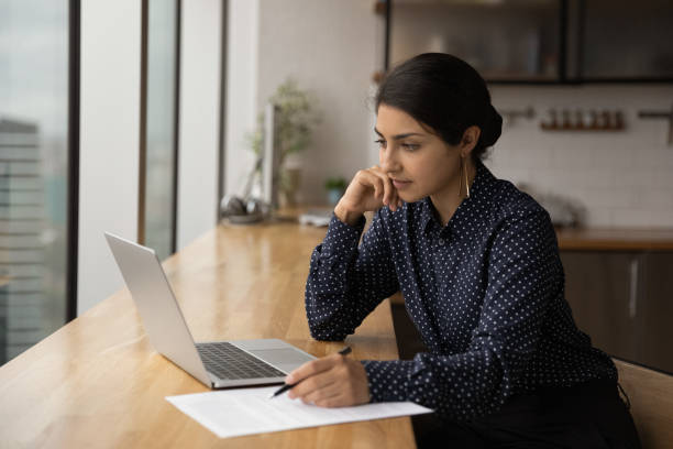 istock Pensive Indian woman work online on laptop 1292931073