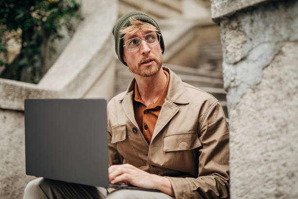 istock Modern man using laptop on steps in city 1292932480