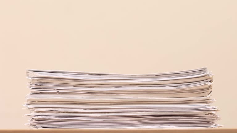 Stack of overload document paper on wooden table - Stop motion animation. Business concept footage.