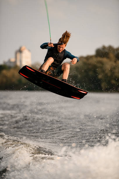 istock young active guy masterfully jumps on wakeboard over water with splashes 1292935147