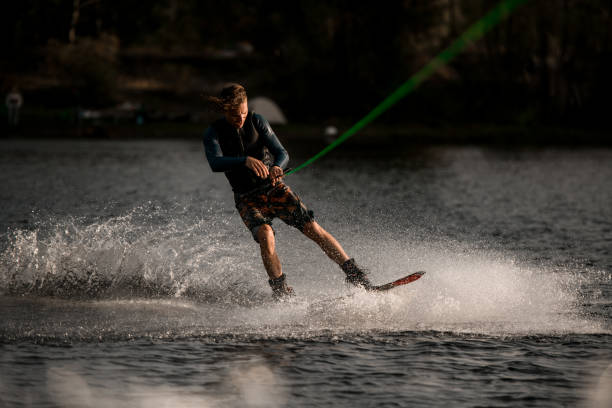 istock young attractive man in wetsuit riding wakeboard fast on splashing river water 1292935306