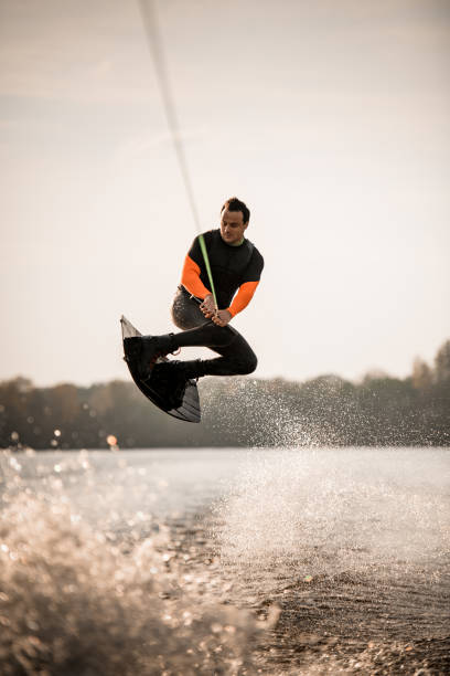 istock man in wetsuit having fun and jumping on the wave on wakeboard. 1292935361