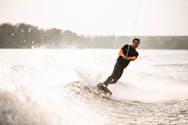istock adult man rides down on wakeboard on splashed river wave from boat 1292936174