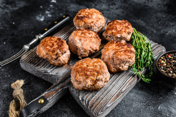 istock Roasted cutlets from beef and pork meat. Black background. Top view 1292942109