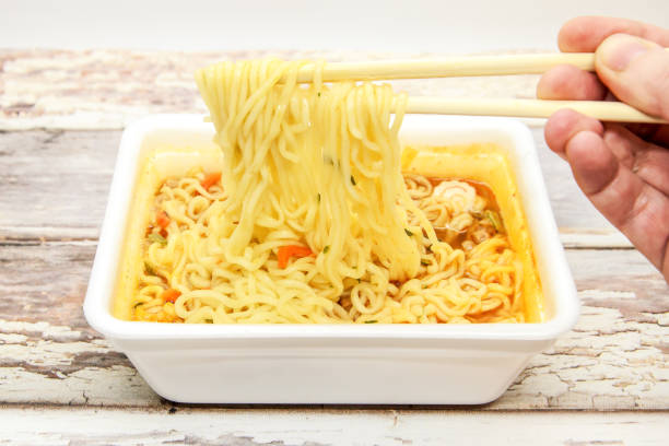 istock Instant noodles with vegetables and spices with red pepper in disposable container with wooden chopsticks 1292942254
