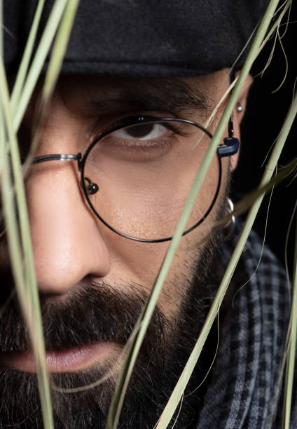 istock Portrait of handsome charismatic man looking towards camera through tree leaves. 1292943775