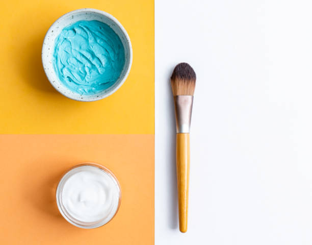 istock Facial mask, face moisturizer and brush on multi colored background with copy space 1292944333