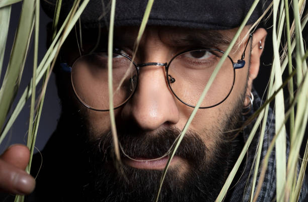 istock Portrait of handsome charismatic man looking towards camera through tree leaves. 1292944347