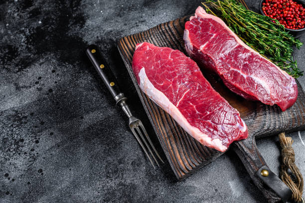istock Raw marbled beef meat sirloin steak. Black background. Top view. Copy space 1292944509