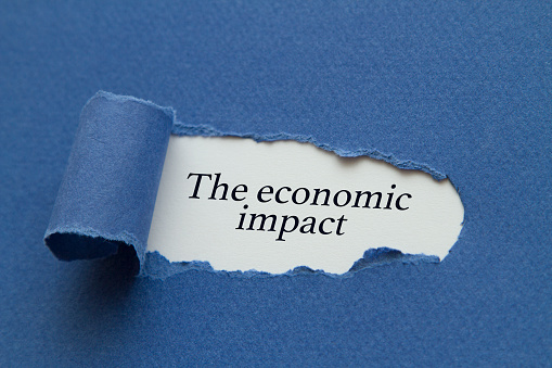 The economic impact message written under torn paper