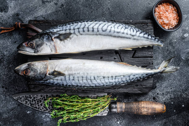 istock Raw fish Mackerel on a wooden cutting board. Black background. Top view 1292944534