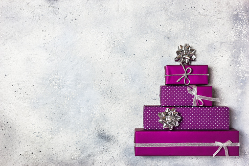 Christmas tree made of purple gifts boxes, flat lay composition. Winter holidays concept. Creative Christmas greeting card.