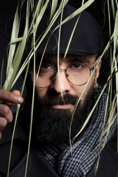 istock Portrait of handsome charismatic man looking towards camera through tree leaves. 1292944656