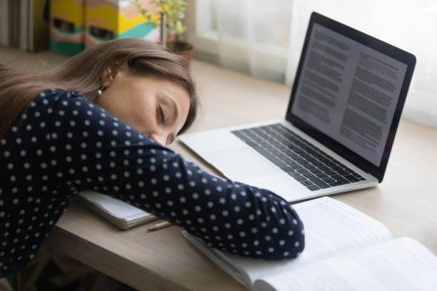 Close up tired young woman falling asleep at work desk Close up tired young woman falling asleep at work desk with laptop and books, lack of sleep and insomnia concept, overworked unmotivated businesswoman or student lying on table with closed eyes narcolepsy stock pictures, royalty-free photos & images