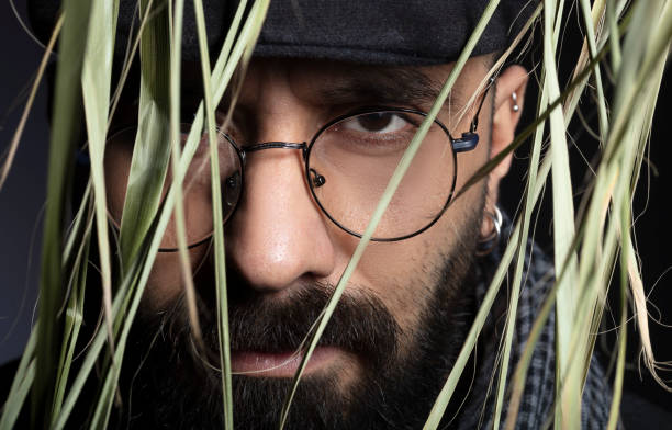 istock Portrait of handsome charismatic man looking towards camera through tree leaves. 1292945381