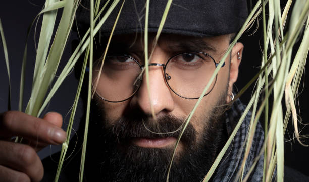 istock Portrait of handsome charismatic man looking towards camera through tree leaves. 1292945551