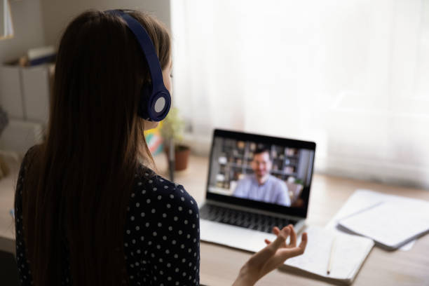 istock Rear view woman wearing headphones using laptop, making video call 1292945665