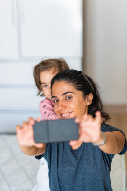 istock Mother and little daughter smiling while taking selfie with cell phone 1292945691