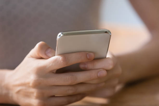 istock Close up young woman holding smartphone, browsing apps, chatting online 1292945697