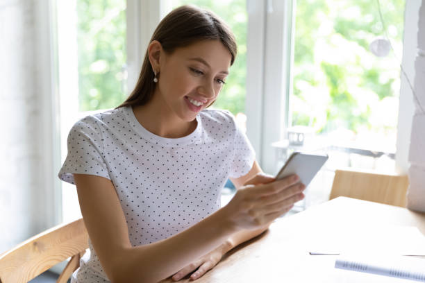 istock Close up smiling woman holding phone, looking at screen, chatting 1292945702
