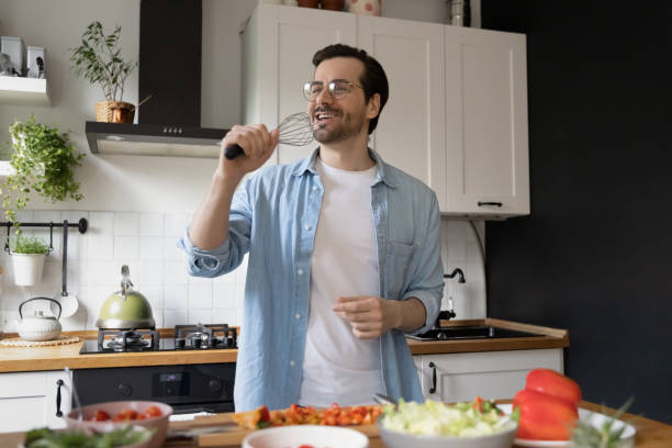istock Smiling funny young man wearing glasses singing into whisk 1292945723
