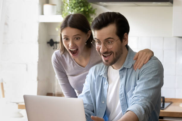 istock Close up amazed couple looking at laptop screen in kitchen 1292945772