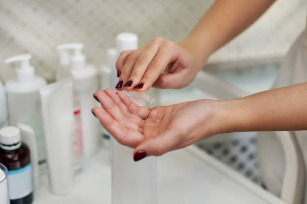 istock Focus on beautician's hands while applying disinfectant gel to hands using a dispenser 1292951089