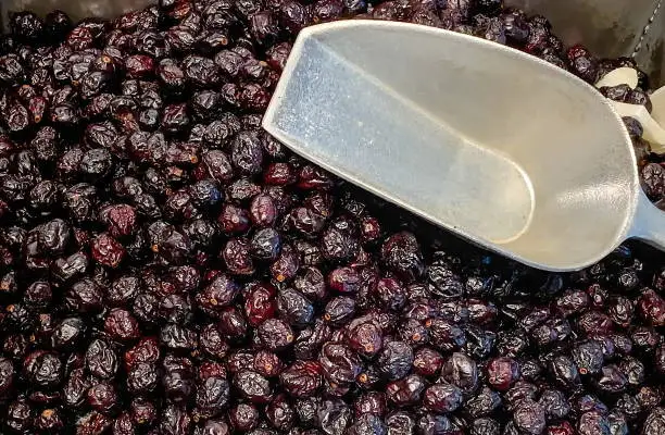 Photo of Dried date fruits on sale and metal forceps at a market or store