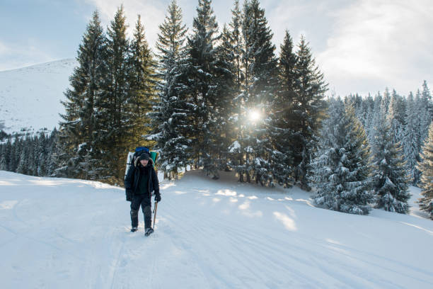 istock Traveler with an ice ax and a backpack walks a snowy mountain forest 1292969981