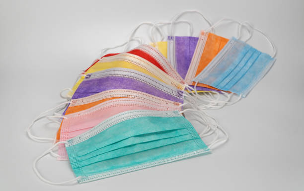 istock Multicolored surgical masks on white background. disposable medical face masks in different colors. Medical respiratory bandage face for protection against corona virus. COVID-19 pandemic Lockdown. 1292973052