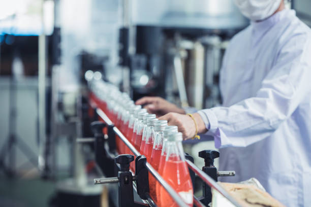 fabbrica di bevande - lavoratore dell'igiene da vicino che lavora controllare il vetro del succo imbottigliato nella linea di produzione - catena di montaggio foto e immagini stock