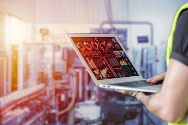 closeup engineer using laptop computer to monitor and checking business data with blur factory background