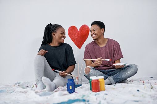 Shot of a young couple painting a heart on a wall