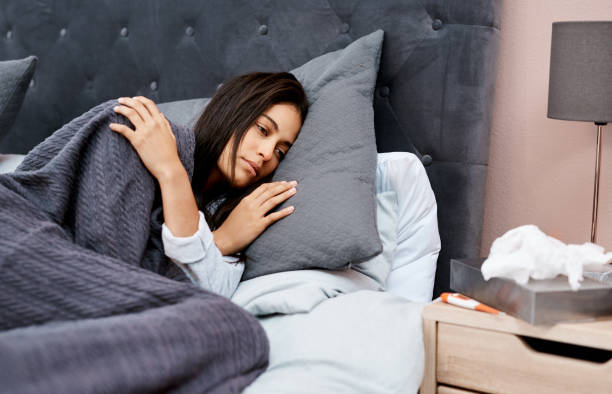 Battling the flu? Stay in bed Shot of a young woman recovering from an illness in bed at home exhaustion stock pictures, royalty-free photos & images