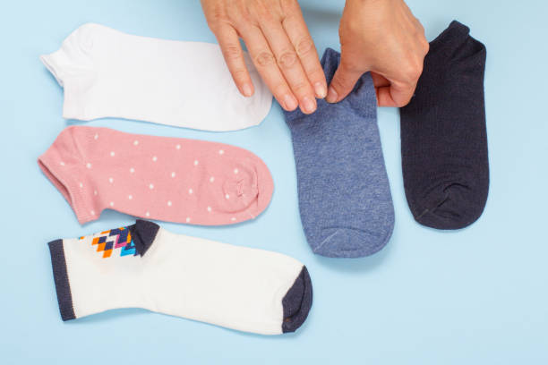 istock Female hands with women socks on blue background. 1292998466