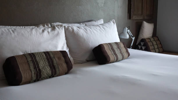 istock Traditional brown fabric pattern throw cushion on white pillow and bed sheet 1293000889