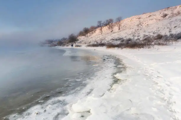 Photo of The frozen river is covered with ice. Sea shore in winter. Noise effect.