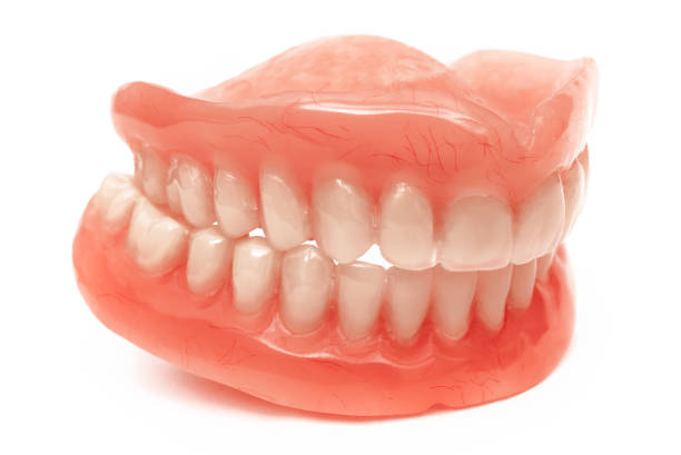 Full removable plastic denture of the jaws. Set of dentures on a white background. Two acrylic dentures. Upper and lower jaws with fake teeth. Dentures or false teeth, close-up. stock photo