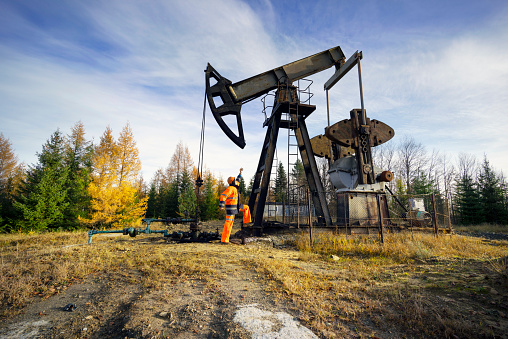 Ancient oil and gas field in the Ukrainian Carpathians, begun under Austria-Hungary, Poland. Gas worker engineer Self-portrait oil worker checks the operation of the pipeline and pump at the beginning of winter.