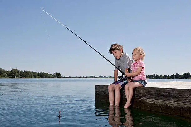 Photo of Brother and sister fishing on dock