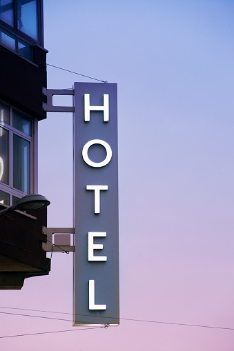 Close-up view of hotel sign on tall building facade at dusk, sunset background. A Coruña, Galicia, Spain.
