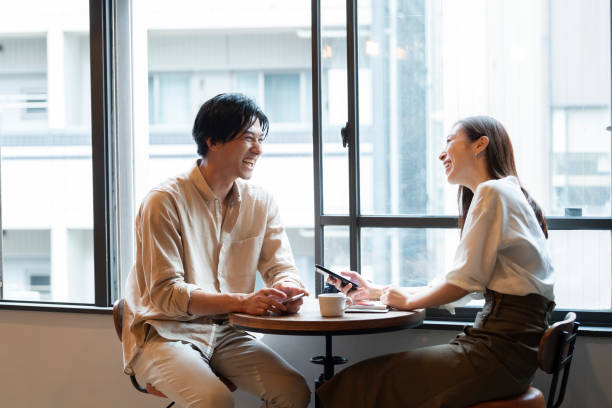 カフェで楽しい会話をしているカップル - women couple men talking ストックフォトと画像